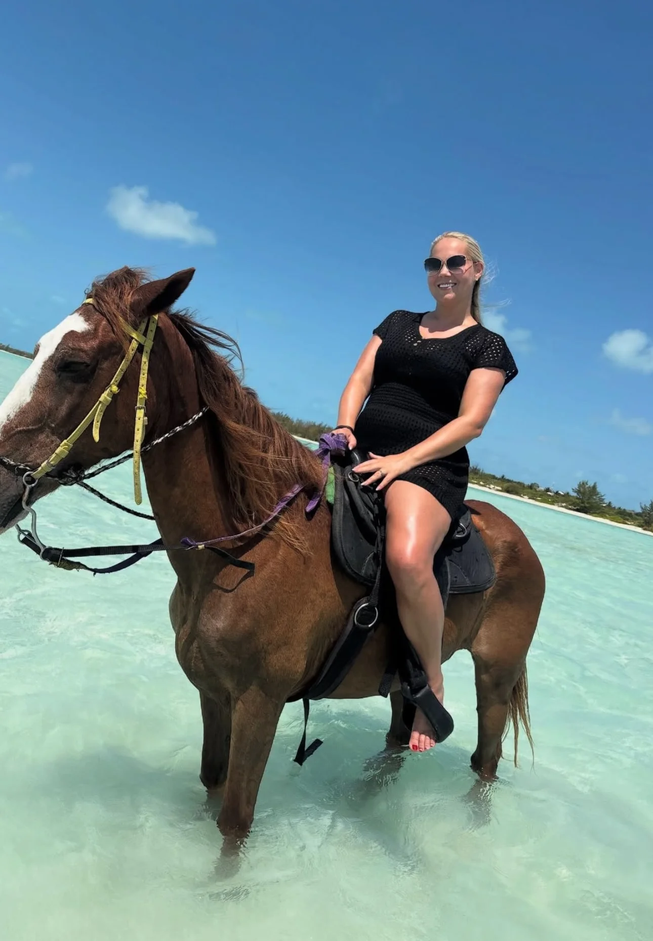 woman wearing black on a horse at the beach