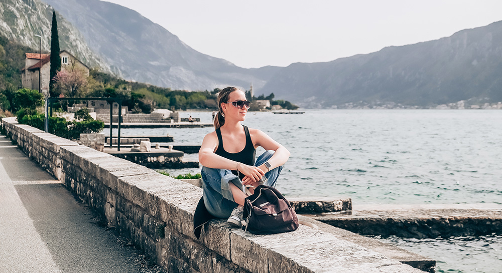A woman sitting on a wall by a lake